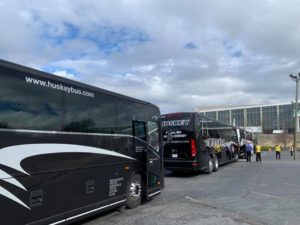 Black Huskey buses lined up in front of a corporate building