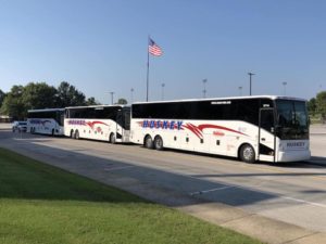 Lineup of Huskey buses in front of a flag pole