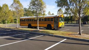Yellow School Bus sitting in a parking lot with trees