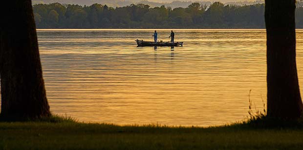 Two People fishing in a boat at sunset on the lake in Kirksville, MO
